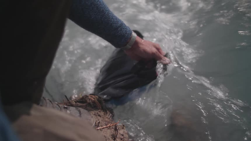 Man fills a water bag on a river