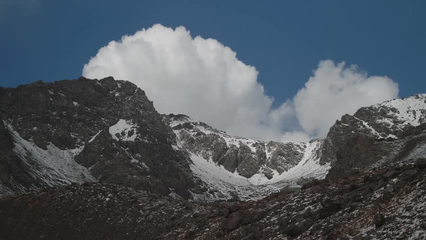 Clouds over the snow covered mountain peaks