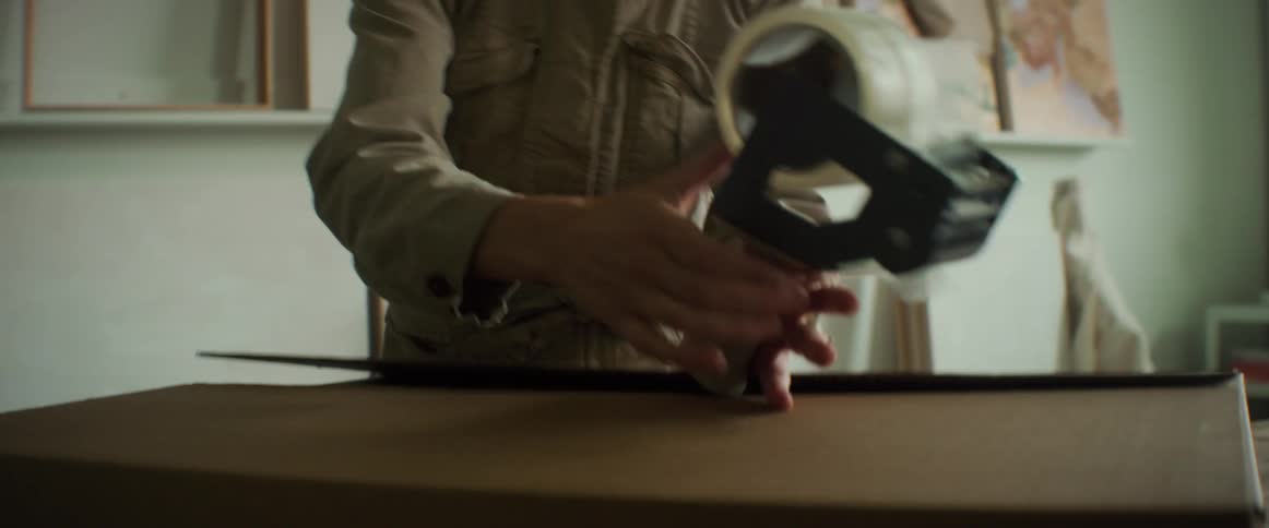 A woman wrapping boxes indoor with a duct tape