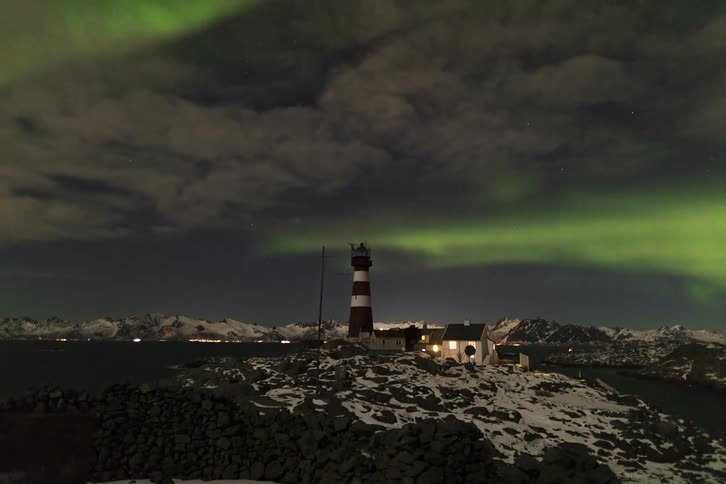 A time lapse shows northern lights passing above a lighthouse