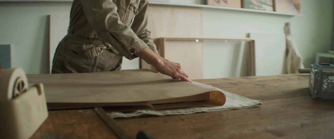Woman wrapping a painting on a table