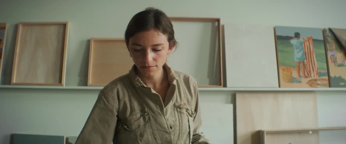 A lady painting while standing by the table inside artwork studio during the day