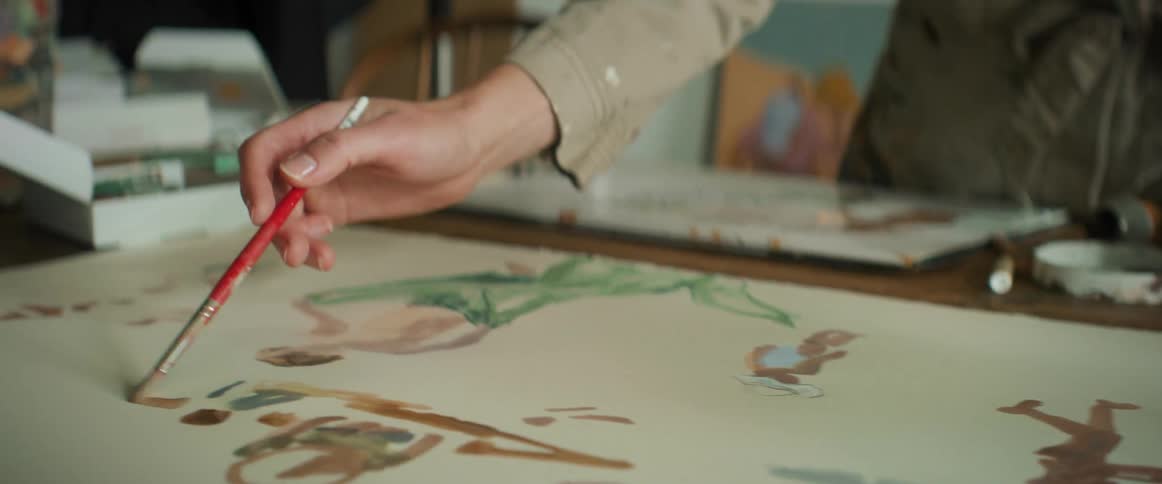 Closeup of a painters hands working on a canvas under the table