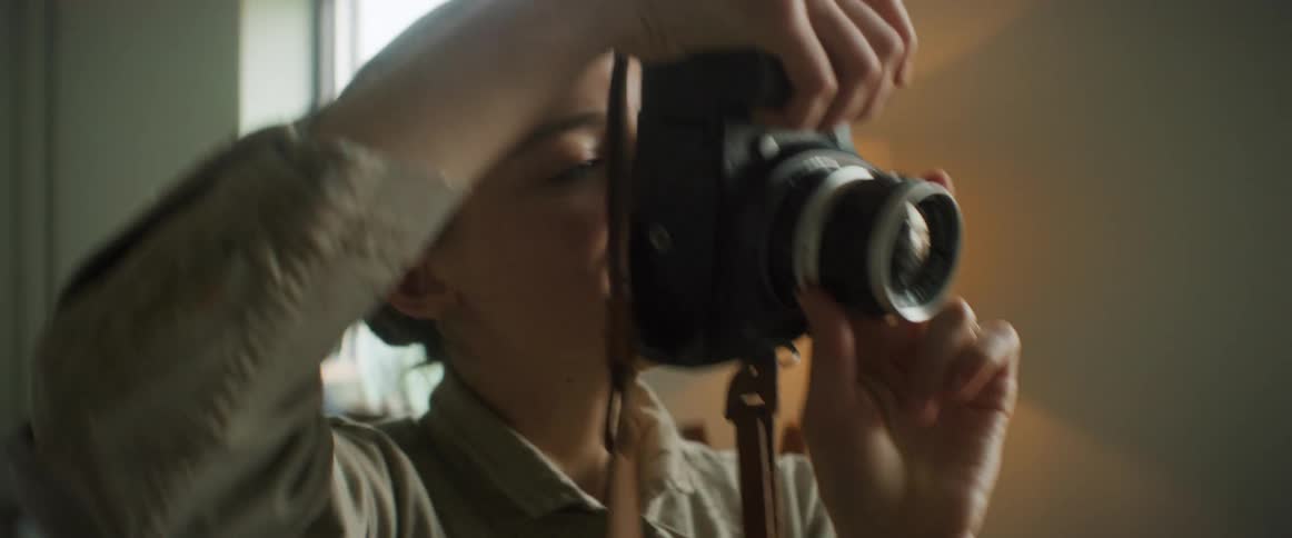 A woman puts a digital camera on her face to take a photo and is happy