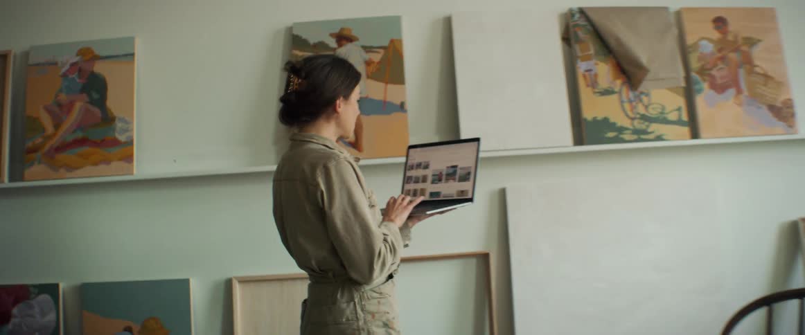 A woman standing with a laptop in her hands in a room