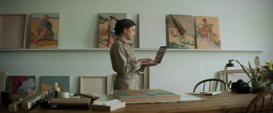 Woman standing and working on the laptop in a room during the day