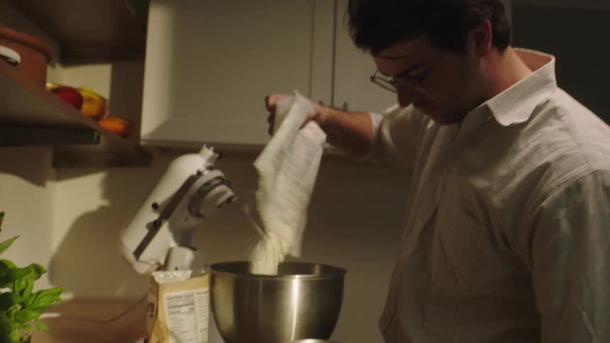 Man cooking and putting wheat into a bowl in the mixer