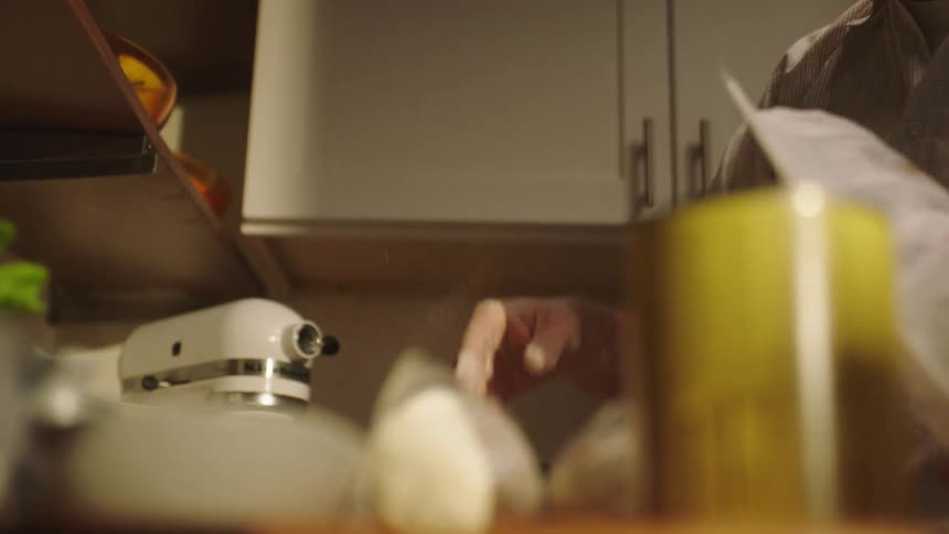 A man is pouring flour onto something on the table using his hand