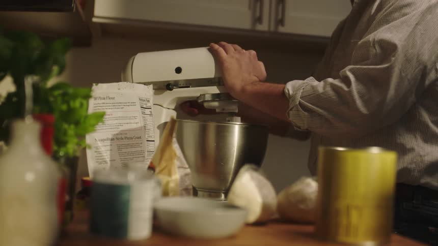 A man is using a mixer in the kitchen