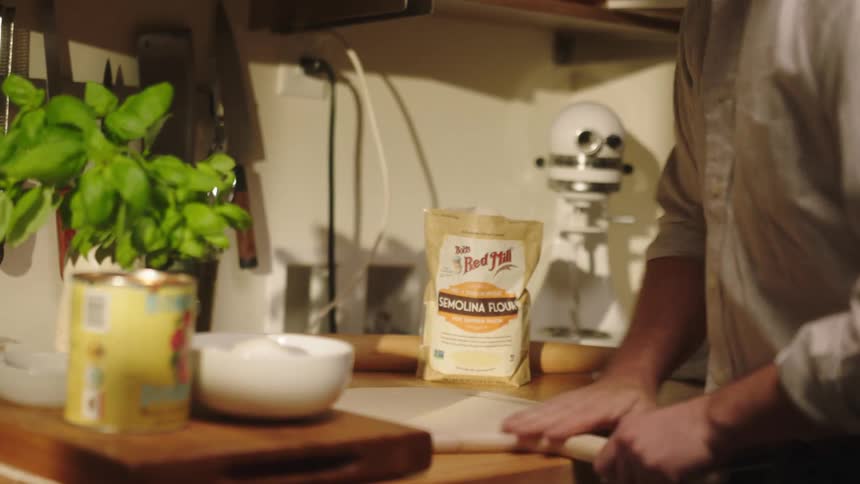 A man is spreading flour on the cutting board