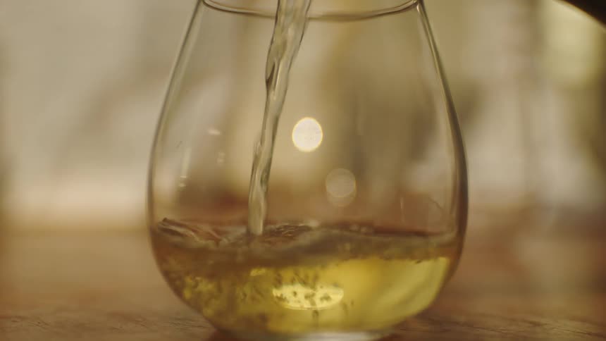 Person pour drink inside a glass cup