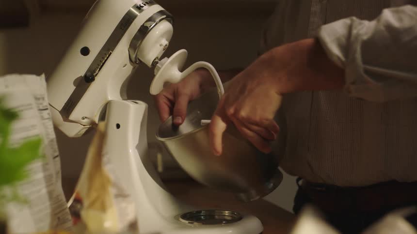 Man cooking and taking a bowl of dough from the mixer