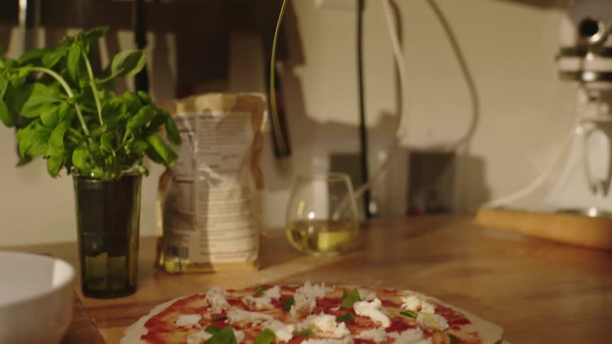 A person preparing a pizza is about to enter the oven