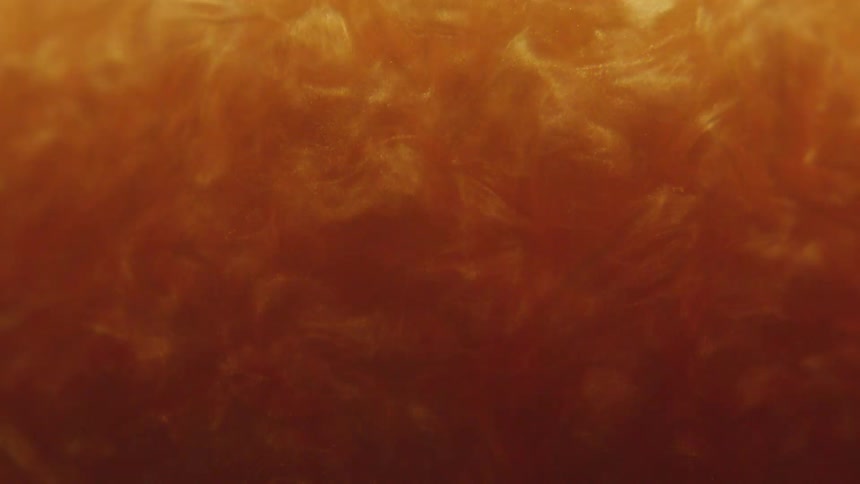 Thick amber shimmering liquid swirling