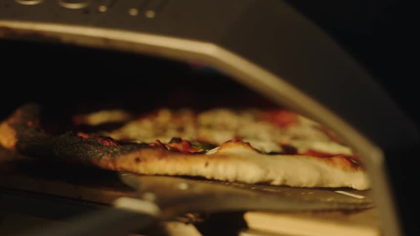 Pizza being placed into an oven to bake