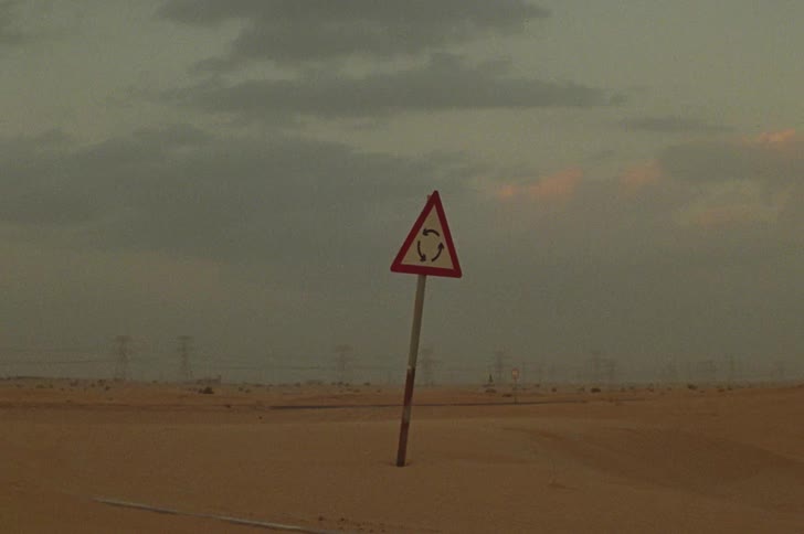 Rotating sign in the midst of the desert with electrical power towers in the background