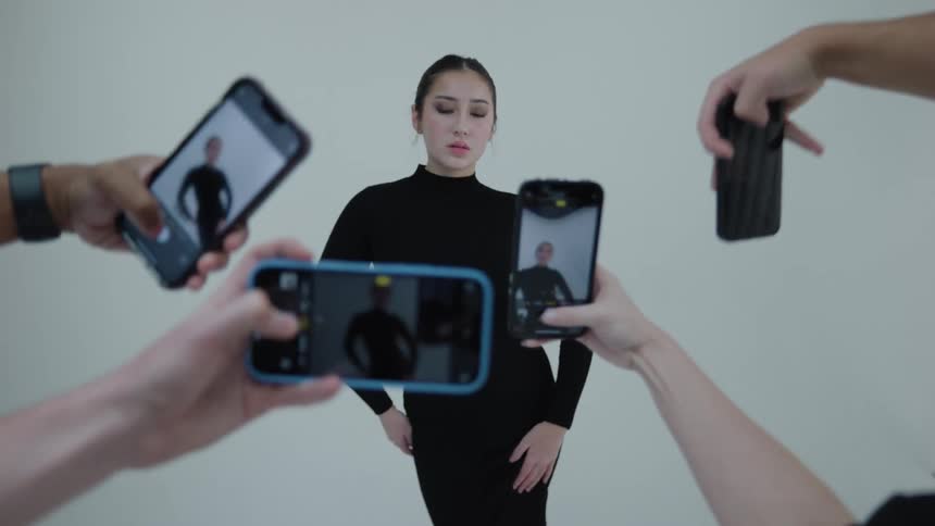 Woman modeling while people take photos of her with smartphones