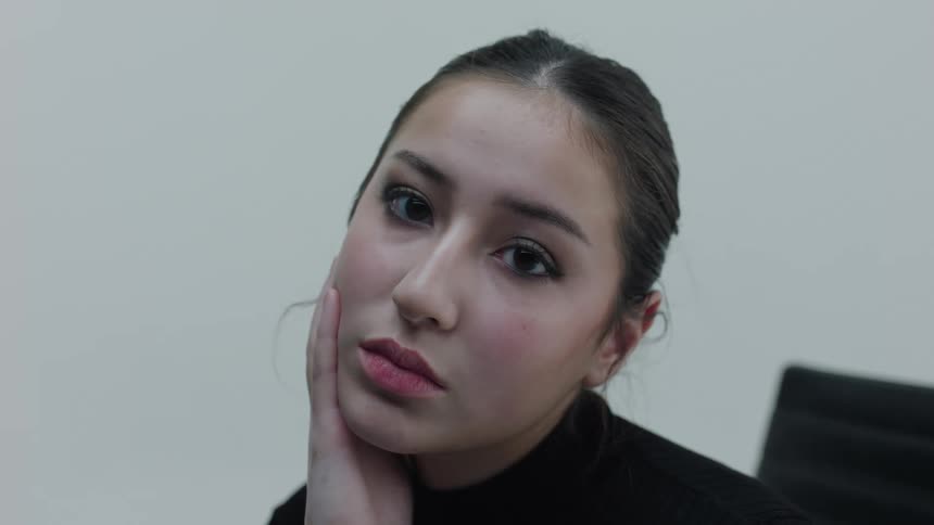 Female with hand on face turns toward camera