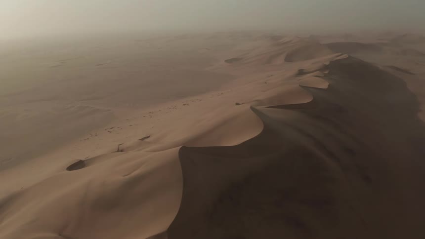 Drifted sand of the desert dunes under a hazy sky