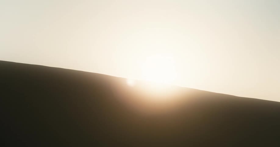 Sun shines over a sand dune at morning