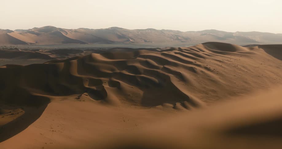Brown sand dunes in the desert under a hazy daytime sky