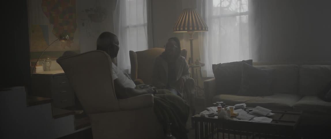 Two people sit in a living room talking