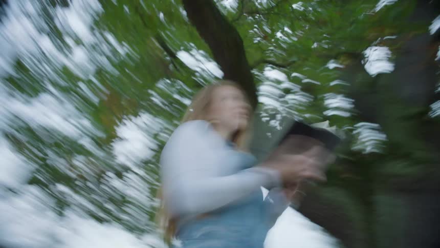 A woman is standing under a tree and spinning around