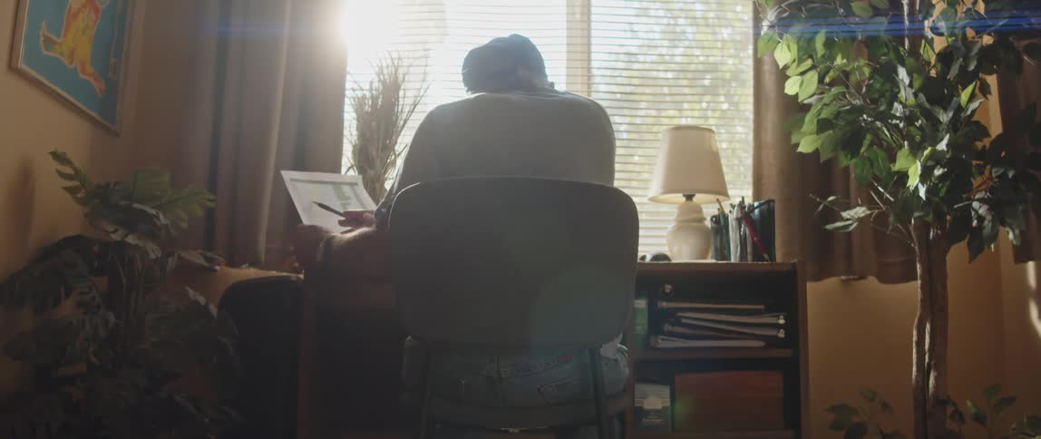 Elderly person sitting at a desk examining information on a document