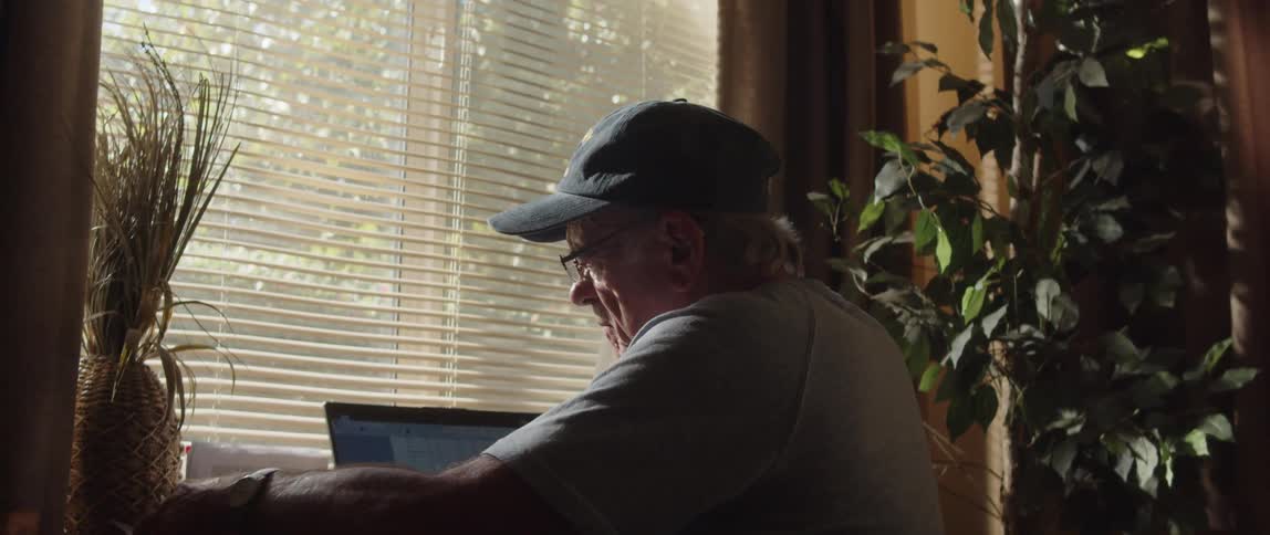 Elderly person sitting going through some documents facing a laptop