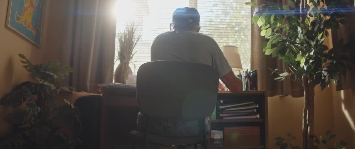 An elderly man sitting behind a desk near the window