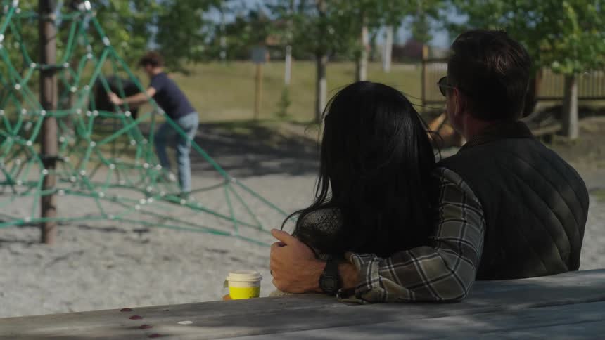 Couple sitting in a park with their child playing
