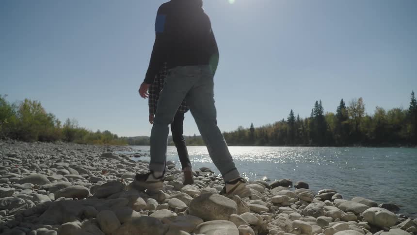 Two men walking among the rocks beside a lake in nature