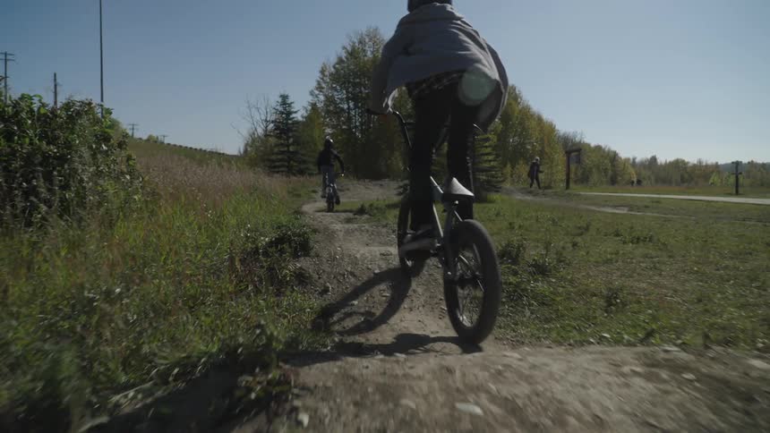 Two young people riding bicycles down a dirt path