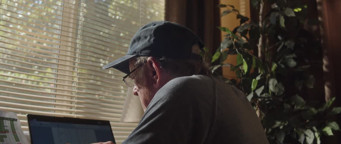 A man is looking at his laptop and a piece of paper