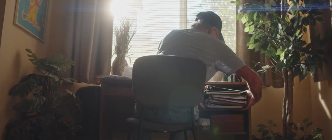 An old man arranging his desk while sitting