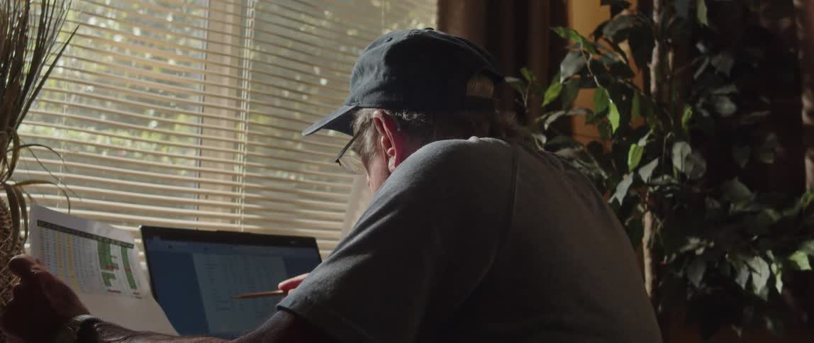 A man looks at a paper and a laptop
