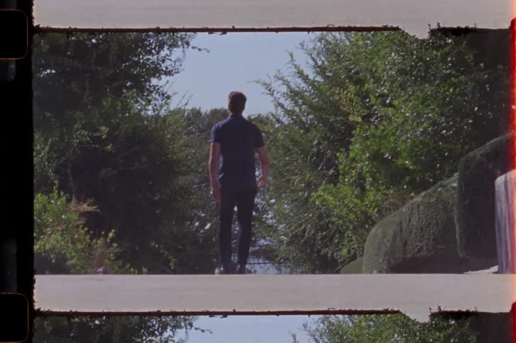View of a man walking away on a narrow sloping street amidst nature