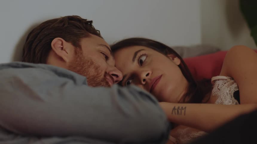 A couple lying in bed holding hands and cuddling