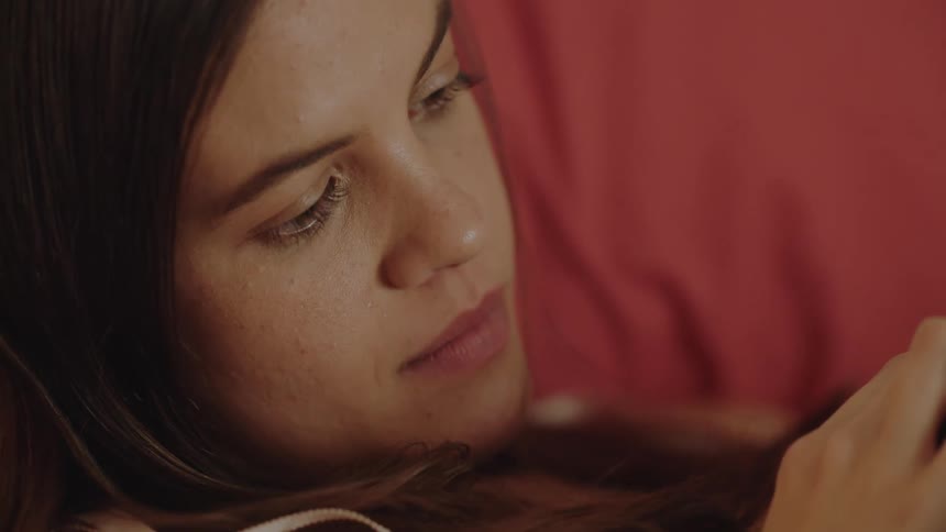 A man and a woman are lying in bed together his head on her lap as she caresses his hair then he moves up closer to her