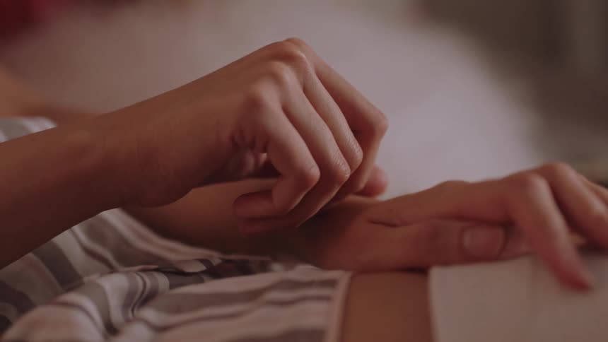 Woman resting in bed touches the skin of her arm