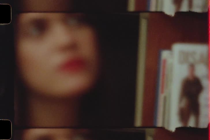 Face of a young woman standing next to a bookcase caught on vintage film