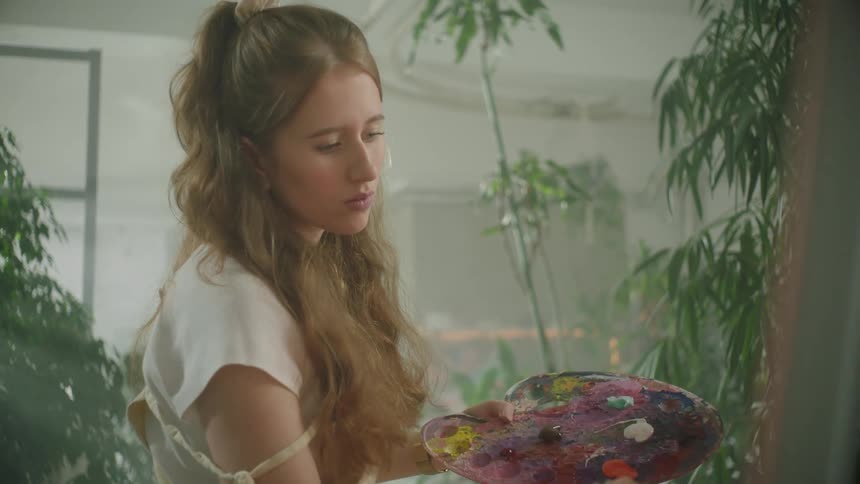Portrait of a painter holding a palette with paint and a brush in the other hand