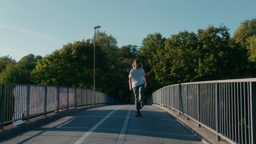 There is a man skateboarding on a bridge in the daytime