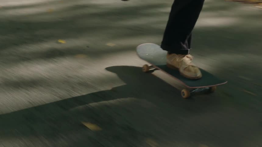 A man skateboards down a trail past an apartment building