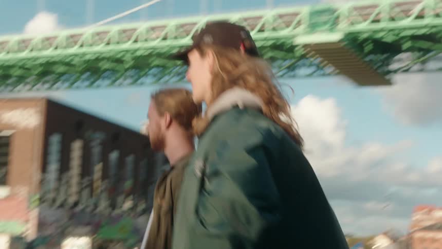 Two men are standing outside talking on a sunny day