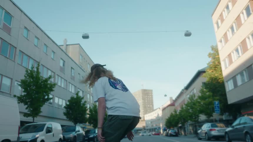 A male skateboarding down a city street jumps on his board