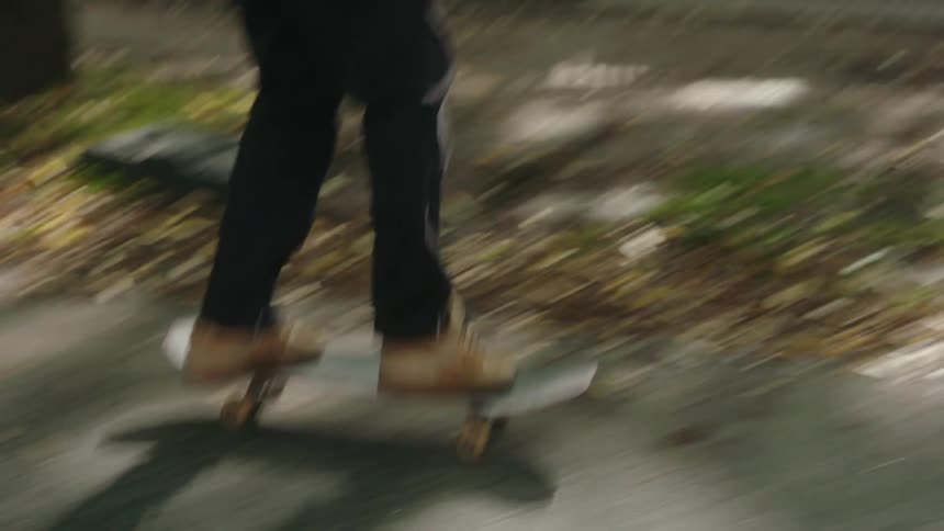 A teenage boy skateboards down a sidewalk alongside a bus