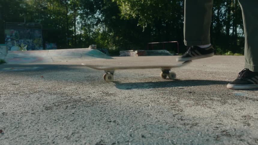 A skateboarder steps on the wheels of his board then flips it up to grab