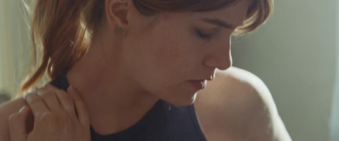 woman with a ponytail rubs her neck to relax after workout
