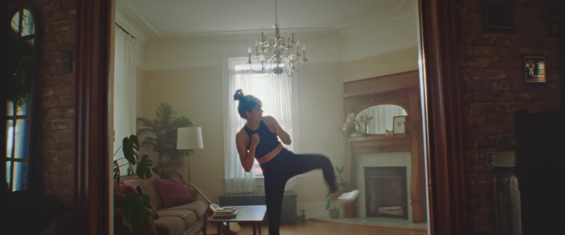 Pregnant woman does sidekicks on a pilates mat in the living room at home